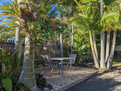 una mesa y sillas en un jardín con palmeras en Sail Inn Motel en Yeppoon