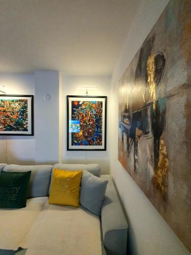 a living room with a couch and paintings on the wall at Negotin Centar Apartment with Parking in Negotin