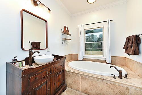 bagno con vasca, lavandino e specchio di Secluded Lodge 8acres Hot Tub, Pingpong pedalboat! a Harrells