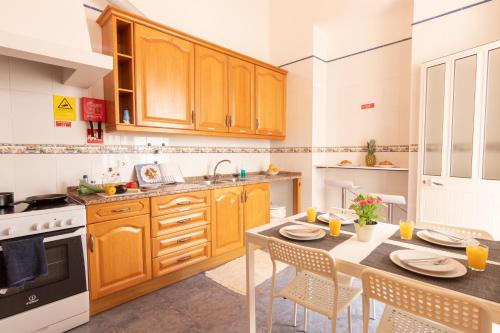 a kitchen with wooden cabinets and a table with chairs at GrowIN Digital Nomads in Faro