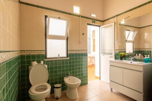 Baño de azulejos verdes con aseo y lavamanos en GrowIN Digital Nomads, en Faro