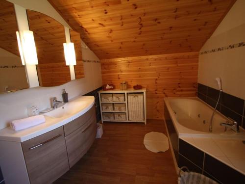 une salle de bain avec une baignoire et un lavabo et une baignoire dans l'établissement Chalet chaleureux avec sauna, terrain, terrasse et babyfoot à Saint-Nabord - FR-1-589-255, à Saint-Nabord