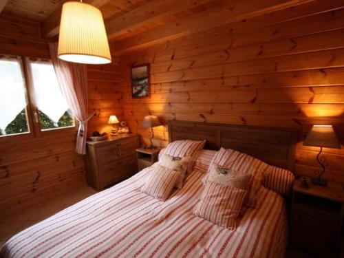a bedroom with a large bed in a log cabin at Chalet haut de gamme avec sauna, terrasse et jardin près de la montagne vosgienne - FR-1-589-185 in Saint-Nabord