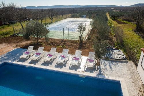 vista aerea su una piscina con sedie e un campo da tennis di Family friendly house with a swimming pool Cista Velika, Vodice - 20227 a Velika Čista