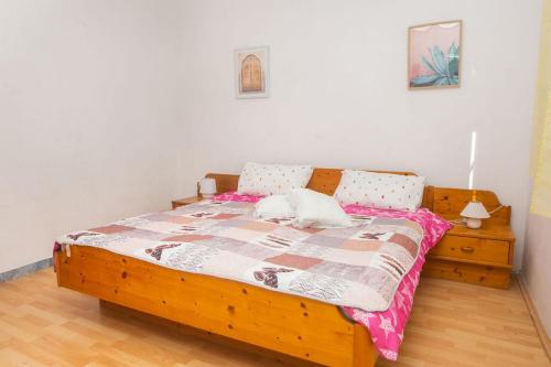 una camera con letto in legno e lenzuola rosa di Family friendly house with a swimming pool Cista Velika, Vodice - 20227 a Velika Čista