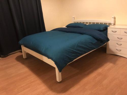 łóżko z niebieskim kocem i białą komodą w obiekcie Private room in Highgate London w Londynie