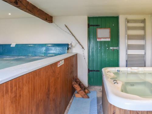 a bathroom with a tub and a green door at The Loft - Ukc6139 in Cartmel