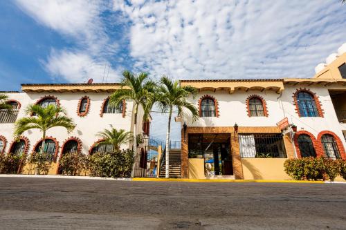 a building with palm trees in front of it at Bungalows Maria Teresa in Rincon de Guayabitos