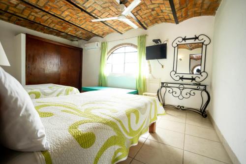 a bedroom with two beds and a mirror on the wall at Bungalows Maria Teresa in Rincon de Guayabitos