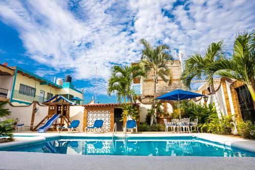 a swimming pool with palm trees and a house at Bungalows Maria Teresa in Rincon de Guayabitos