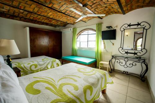 a bedroom with two beds and a mirror and a window at Bungalows Maria Teresa in Rincon de Guayabitos