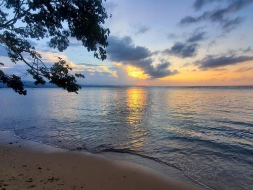 einen Sonnenuntergang über dem Wasser mit der Küste in der Unterkunft Hanas paradise in San Felipe de Puerto Plata