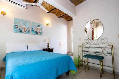 a bedroom with a blue bed and a mirror at Bungalows Maria Teresa in Rincon de Guayabitos