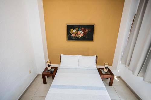 a bedroom with a bed with two tables and a painting at Bungalows Maria Teresa in Rincon de Guayabitos