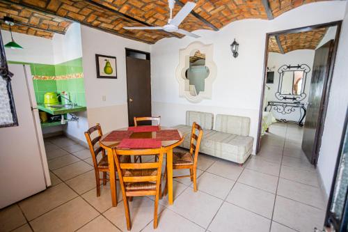 a dining room with a table and chairs and a couch at Bungalows Maria Teresa in Rincon de Guayabitos