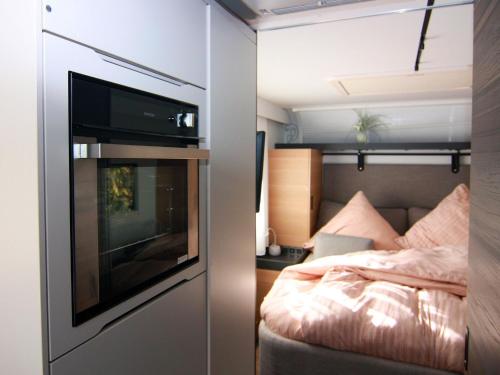 a small bedroom with a bed and a tv in a trailer at Dreamer luxury caravan on the backwaters, Lütow in Lütow