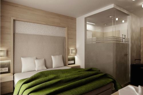 een slaapkamer met een bed met een groene deken bij Hotel Garni Hubertus in Tirolo