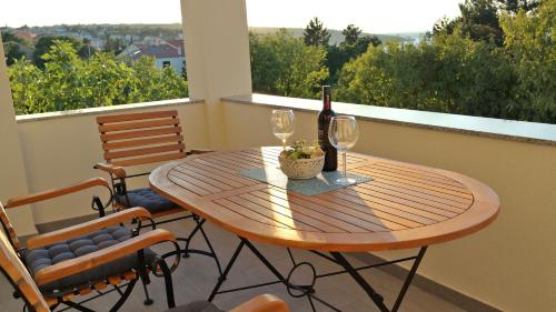 a table with a bottle of wine and two glasses at Apartment Karmen in Šilo