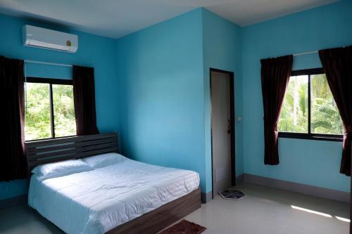 1 dormitorio azul con 1 cama y 2 ventanas en WS HOUSE KRABI, en Ban Ko Kwang