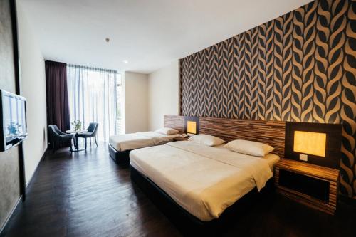 a hotel room with two beds and a television at Waterfront Boutique Hotel in Port Dickson