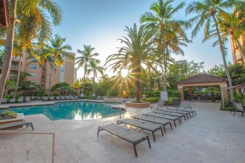 a pool at the resort with lounge chairs and palm trees at Spacious 3 Bedroom Condo in Aventura in Aventura