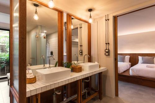 two sinks in a bathroom with a bed and a mirror at GalileOasis Boutique Hotel in Bangkok