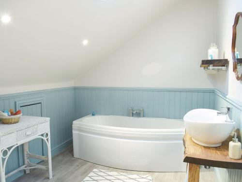 ein Badezimmer mit einer weißen Badewanne und einem Waschbecken in der Unterkunft Glen Rosa in Dalrymple