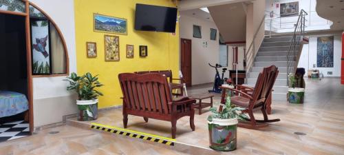 eine Lobby mit Stühlen, einem TV und einer Treppe in der Unterkunft Hospedaje Paraíso in Tingo María