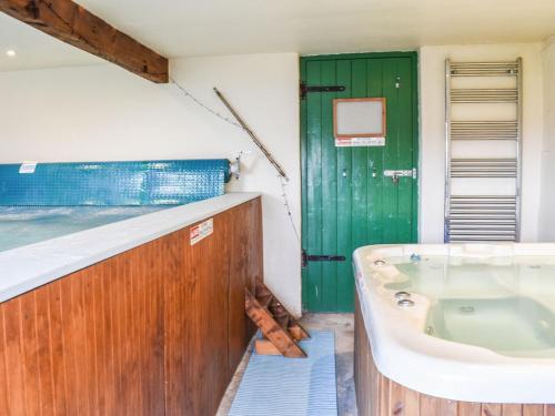 a bathroom with a tub and a green door at The Cottage - Ukc6140 in Cartmel