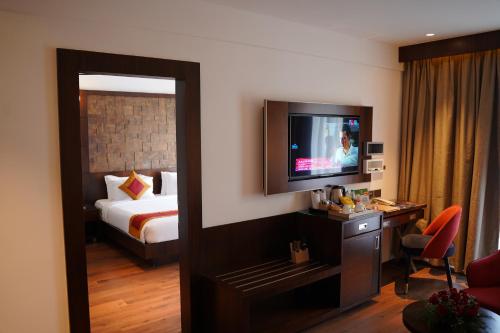 a hotel room with a bed and a television at Saugandhika West Gate in Wayanad