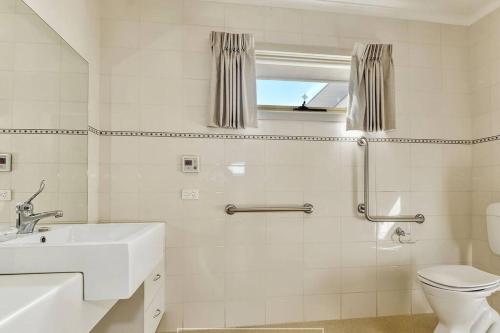 Baño blanco con lavabo y aseo en Central Villa/Two King beds/Disabled/Family/Pets, en Maryborough