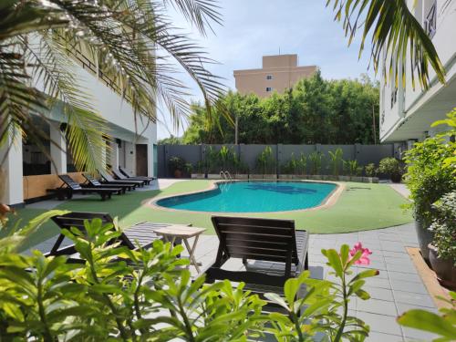 a courtyard with a pool and chairs and a building at The Chanthong Residence and Hotel Pattaya in Pattaya South