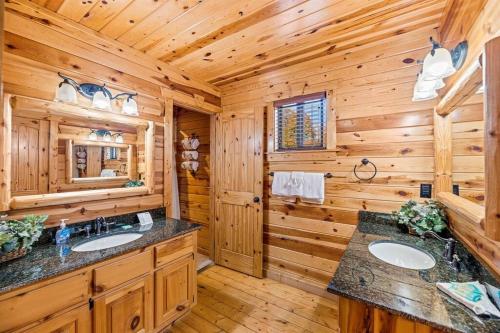 baño con cabina de madera, 2 lavabos y espejo en Bear Tracks, en Gatlinburg