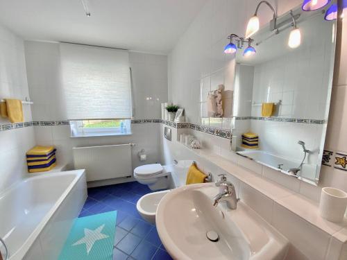 La salle de bains est pourvue d'un lavabo, d'une baignoire et de toilettes. dans l'établissement Gästehaus Backes, à Eppelborn