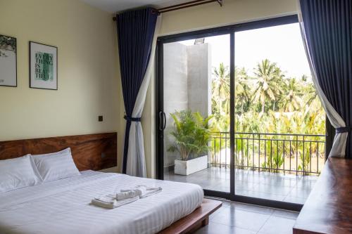 a bedroom with a bed and a large sliding glass door at Kampot Tropical Village in Kampot