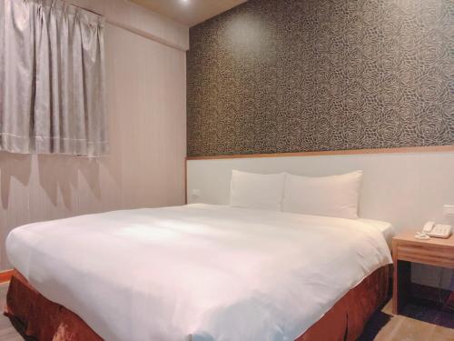 a bedroom with a large white bed and a telephone at Centre Hotel in Kaohsiung