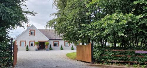 Uma casa branca com um portão à frente. em LittleField B&B Durrow, Laois em Durrow