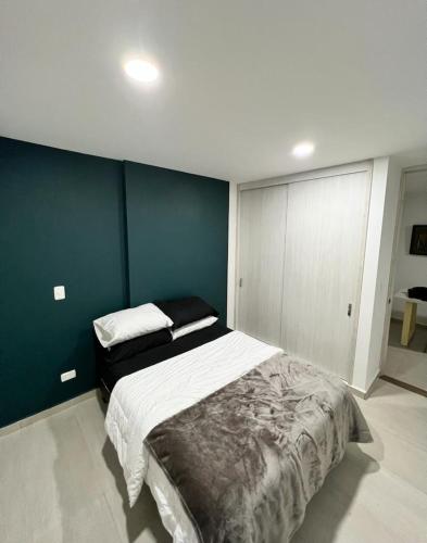 1 dormitorio con 1 cama grande y pared azul en Apartamento en el norte con parqueadero y vista, en Armenia