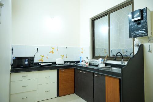 a kitchen with a sink and a microwave at Shri Mahamaya in Panaji