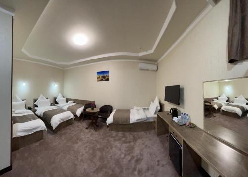 Habitación de hotel con 2 camas y TV de pantalla plana. en Khan Palace Hotel, en Yakkasaray