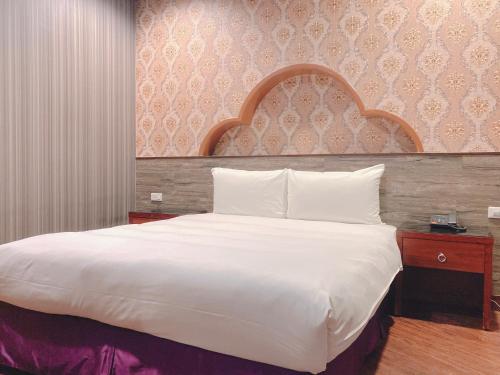 a bedroom with a large white bed with a wooden headboard at Centre Hotel in Kaohsiung
