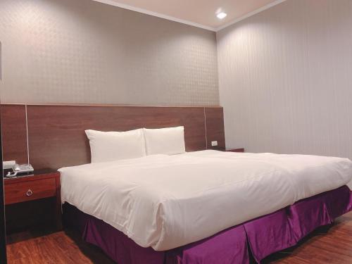a bedroom with a large white bed with a wooden headboard at Centre Hotel in Kaohsiung