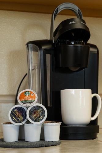 a coffee maker and coffee cups on a counter at Lazy Squirrel - Cozy Family House with Full Game Room in Kernville