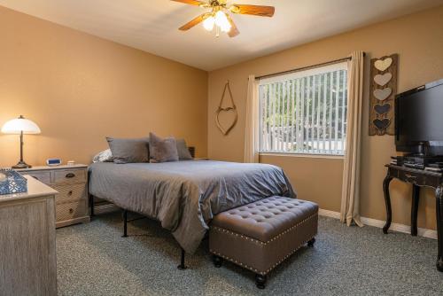 a bedroom with a bed with a ceiling fan and a window at Lazy Squirrel - Cozy Family House with Full Game Room in Kernville