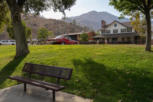 a park bench sitting in the grass next to a house at Lazy Squirrel - Cozy Family House with Full Game Room in Kernville