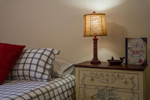 a lamp on a night stand next to a bed at Lazy Squirrel - Cozy Family House with Full Game Room in Kernville