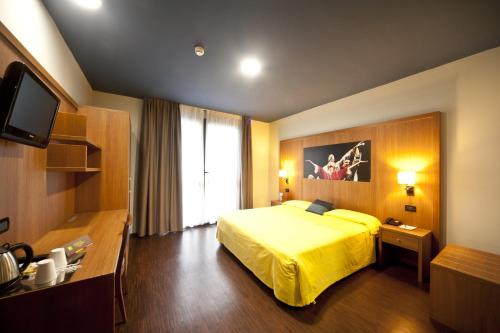 um quarto de hotel com uma cama amarela e uma televisão em Ibis Styles Parma Toscanini em Parma
