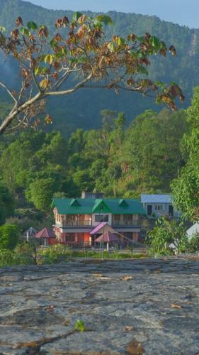 a house with a green roof in front of a mountain at Abhinay Natural Homestay by StayApart in Gorubathān