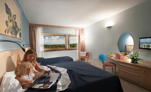 two children sitting on a bed in a bedroom at Grand Hotel Continental in Tirrenia