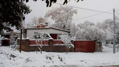 een huis bedekt met sneeuw met een rood hek bij El jazmín in Villa Santa Cruz del Lago